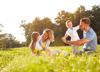 Eltern mit Sohn und Tochter auf einer grünen Wiese