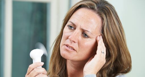 Eine Frau verwendet einen kleinen Ventilator, um sich abzukühlen.