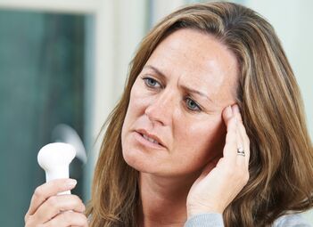 Eine Frau verwendet einen kleinen Ventilator, um sich abzukühlen.